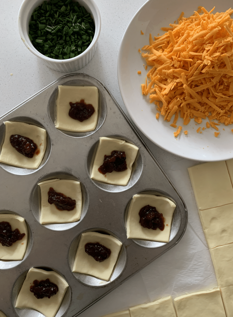 Pastry squares topped with red onion chutney with Red Leicester cheese and chopped chives on the side.
