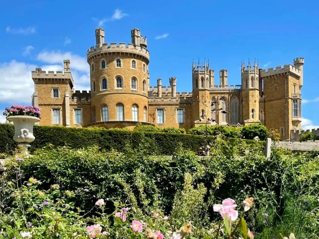 Belvoir Castle exterior with the turret in the summer and shrubs, wild flowers and green grass surround the full castle length