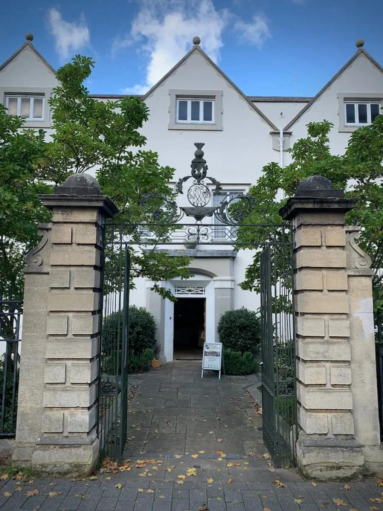 Exterior of Newarke Houses Museum with white pillars and tall trees framing the entrance of the white washed building