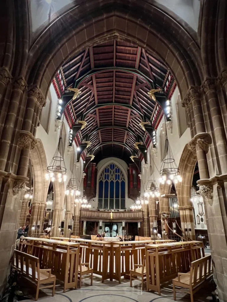 Leicester Cathedral alter details with high ceilings of the cathedral and large stained glass windows. Included are the elaborate pews and archways.