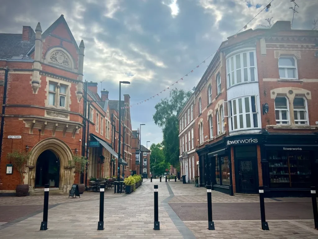 St Martins & Loseby Lane with Sonrisa and Flowerworks in the image behind black pedestrian only bollards.