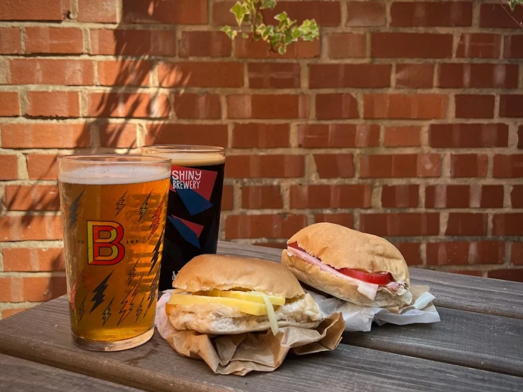 A fruit beer and a stout at The Castle, Leicester. There is also a cheese and tomato and cheese and onion cob on the outside bench seating together with the drinks