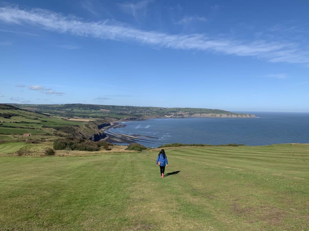 Ravenscar coast with Bejal walking down the cliff with the sea and more cliffs in the background