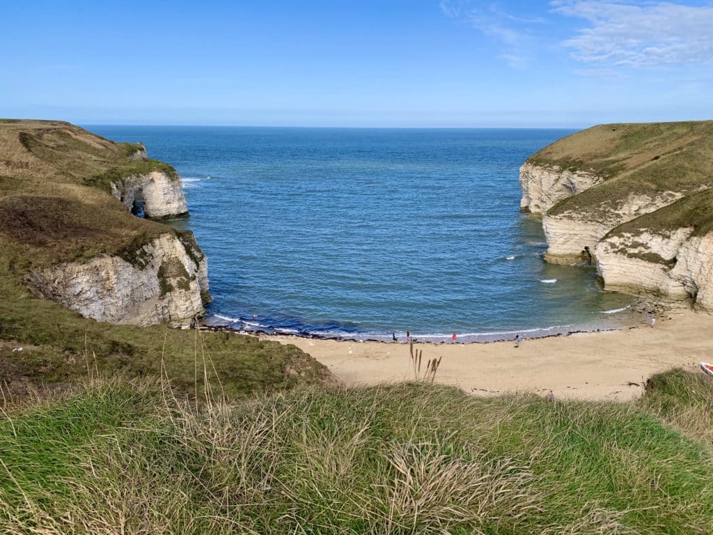 Flamborough Bay with white cliffs and golden sand where children are lpaying 