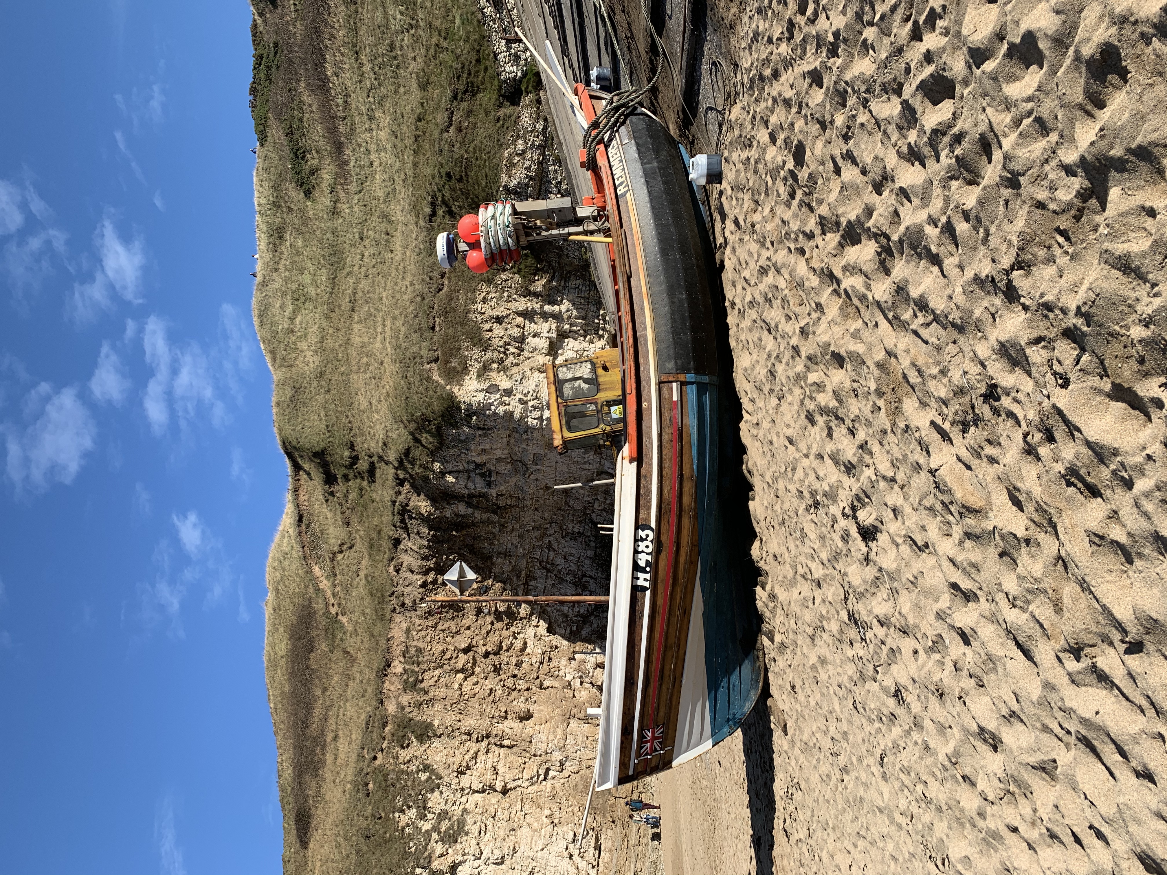 Flamborough fishing boats on the golden sand and green grass covered hills at the back
