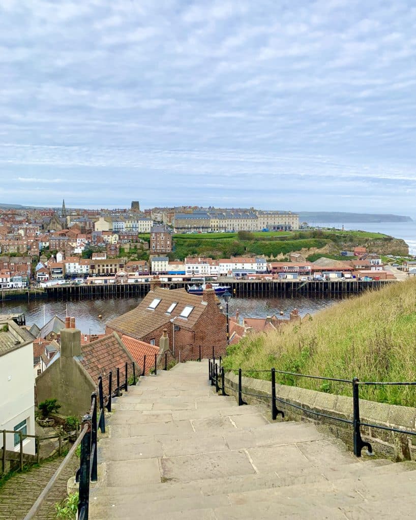 The steps leading down from Whitby Abbey with views of the town and Whale Bone Arch in the distance