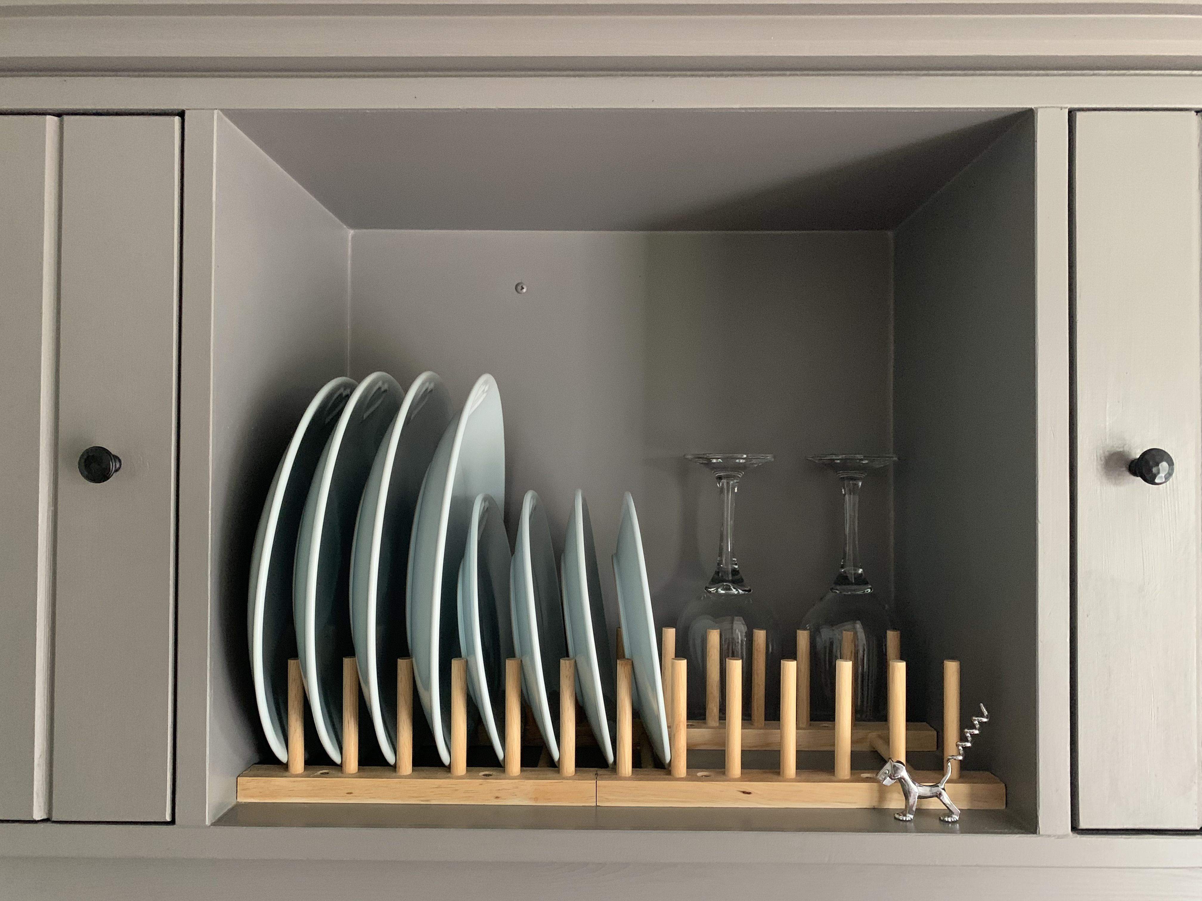 Duck-egg blue Kitchen Plates in a wooden rack in the middle of teh sage green cabinets in the shepherd's hut, Norfolk