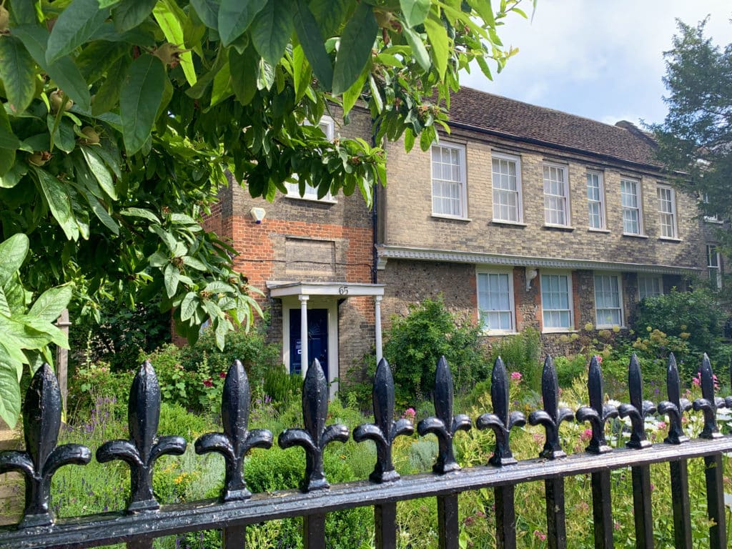 The Norwich cathedral Herb Garden with overgrown herbs, flowers and trees growing around the gate and inside.