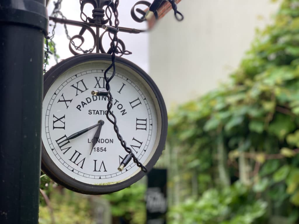 The Folly Tearoom, Norfolk hanging clock just outside teh oearooms which says  Paddington Station on it and is black in colour.