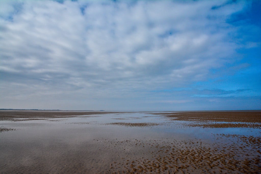 Bright blue sky with beautiful clouds and the sand in the early morning at Brancaster Beach, Norfolk