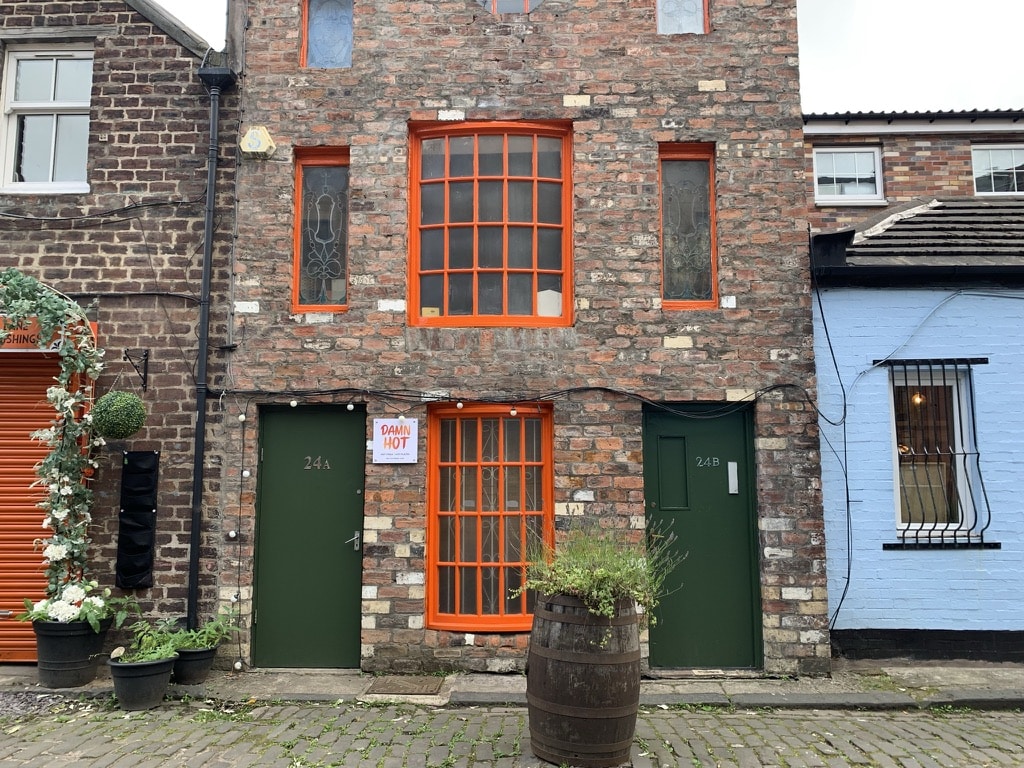 The Hidden Lane, Glasgow building with green doors, orange window frames and cobbled stone streets.