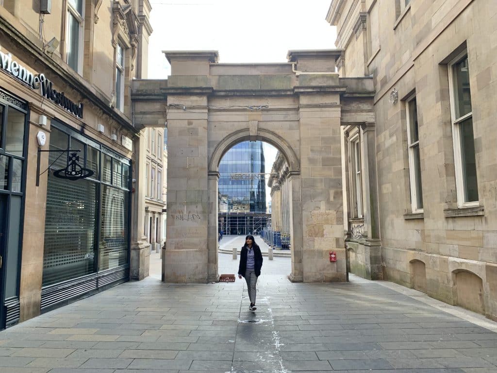 Bejal walking through an archway in the The Merchant City, Glasgow