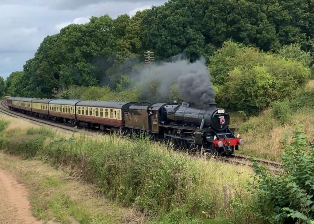 Great Central Railway steam engine in Swithland, Leicestershire  photographed from a bridge in the National Forest. There is black smoke coming out of the top 