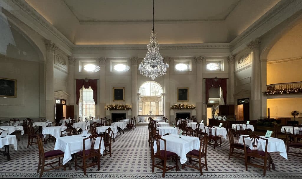 The Pump Room Restaurant room with tables and chairs set up fro afternoon tea with a big crystal chandelier handing from the ceiling in the centre of the room, in Bath