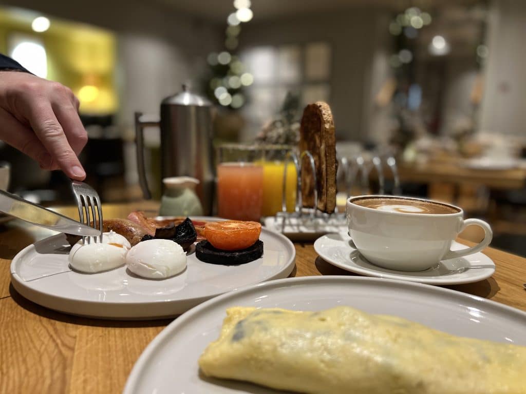 Breakfast at The Queensberry Hotel, Bath. A vegetarian omelette with cappuccino and Dr C is cutting into a poached egg on an off-white earthenware plate