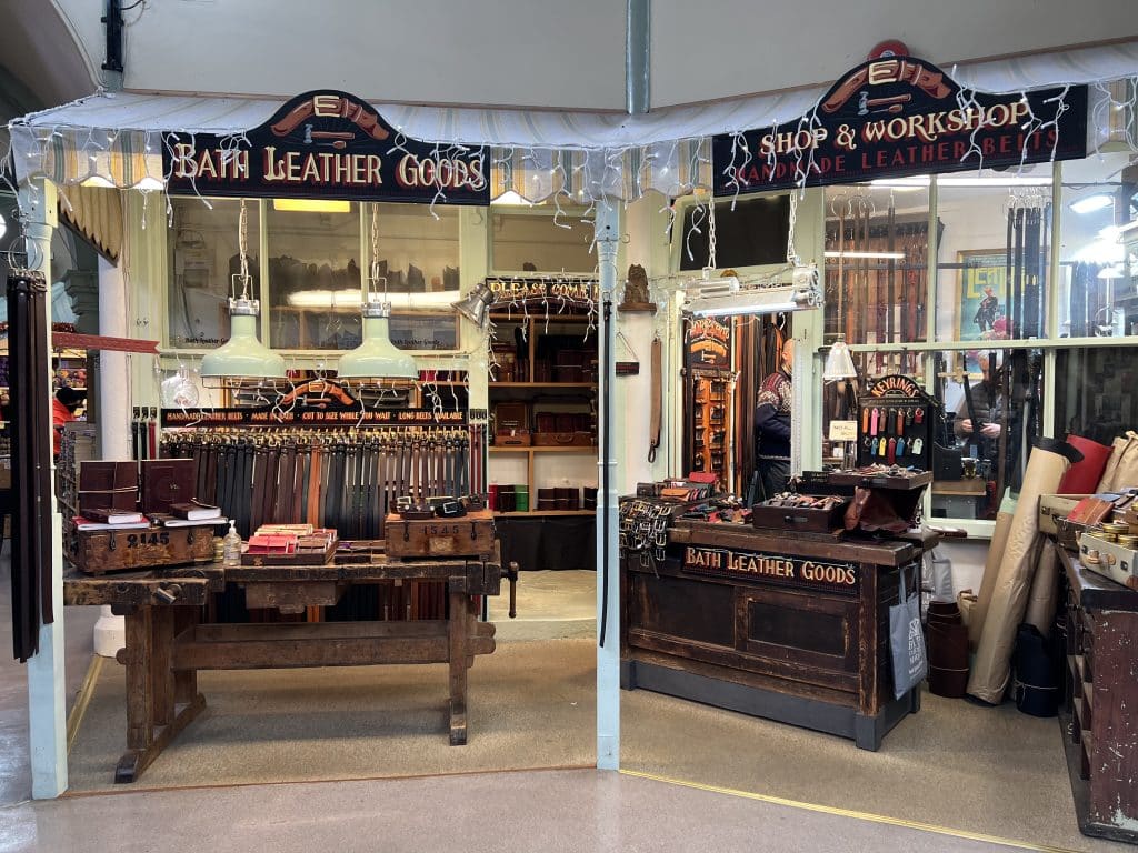  Leather Goods, and workshop stall inside the Guildhall Market in Bath. There are belts and other leather good son display 