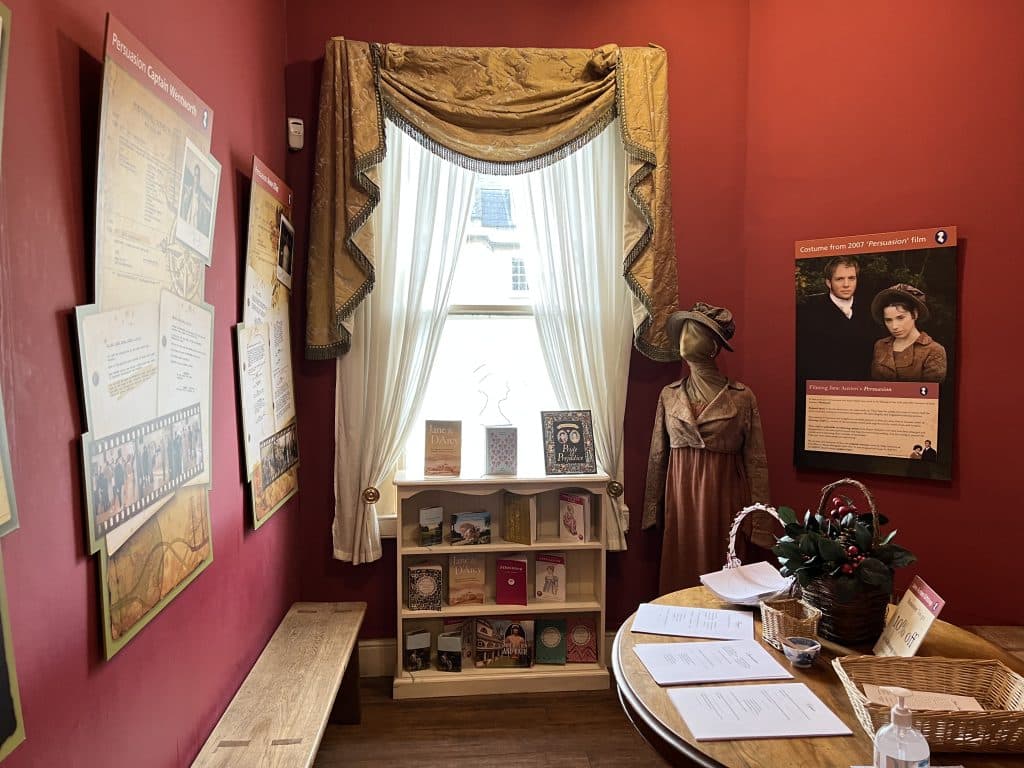 The Jane Austen Centre Interiors with draped curtains and red walls with informative posters on the walls, Bath