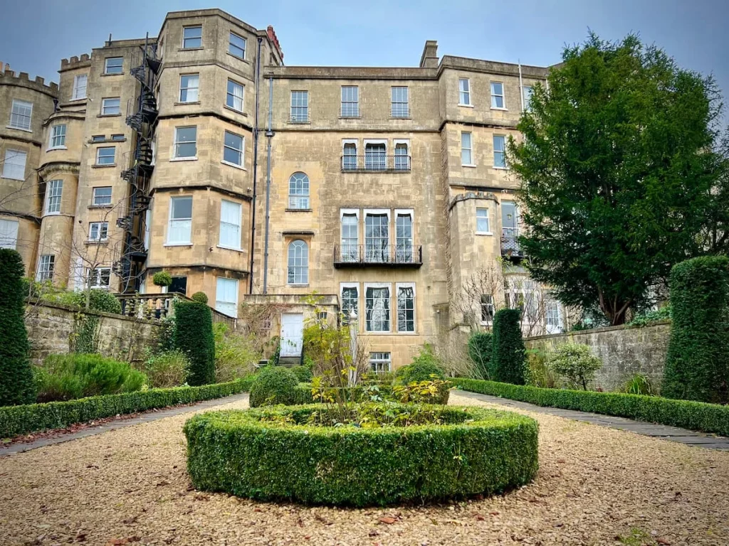 The Georgian Garden, Bath. The gardens are infront of a big townhouse on the Crescent and has variousr green bushes and flower beds as well as trees within it's small grounds.