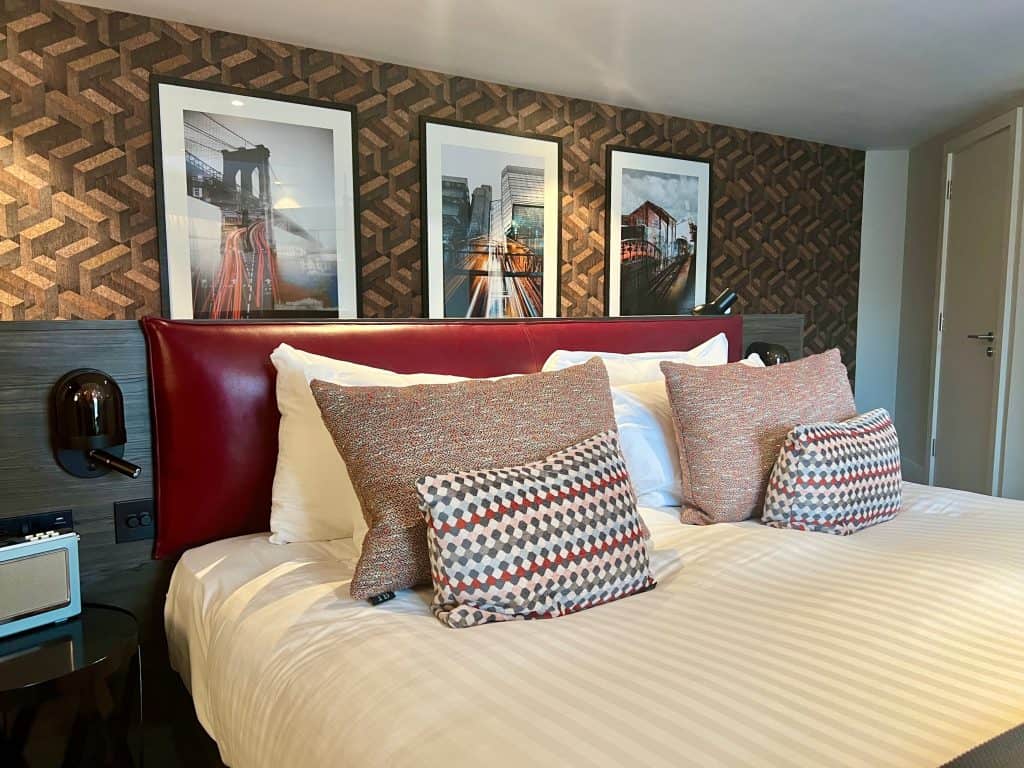 Hotel Brooklyn bedroom, featuring large bed, scatter cushions and photos in background