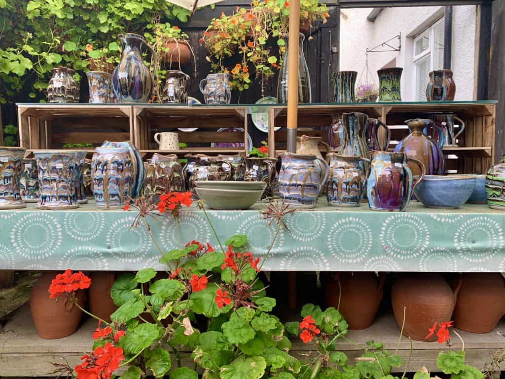 Villages and towns in Fife: Crail Pottery, Fife Coast laid out in a table display with red flowers