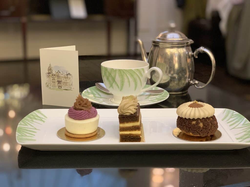 Balmoral Afternoon Tea with small chocolate sweets and a teapot and tea cup in the back. Located in Edinburgh
