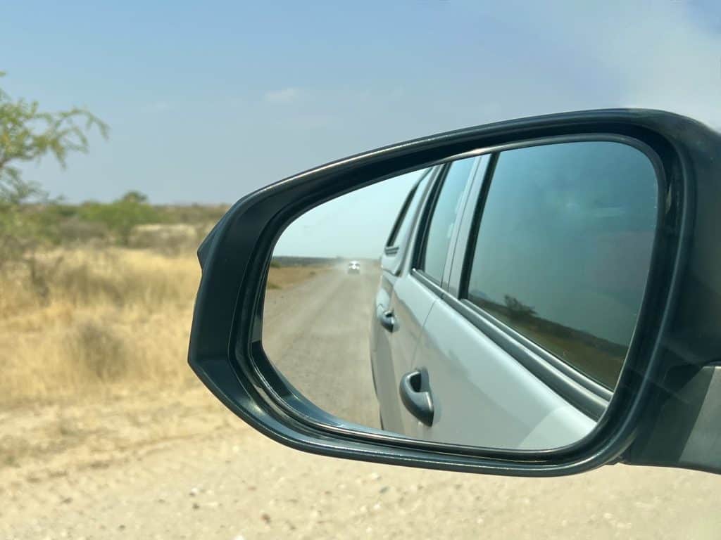 Driving in Namibia Side mirror with car and dust reflection