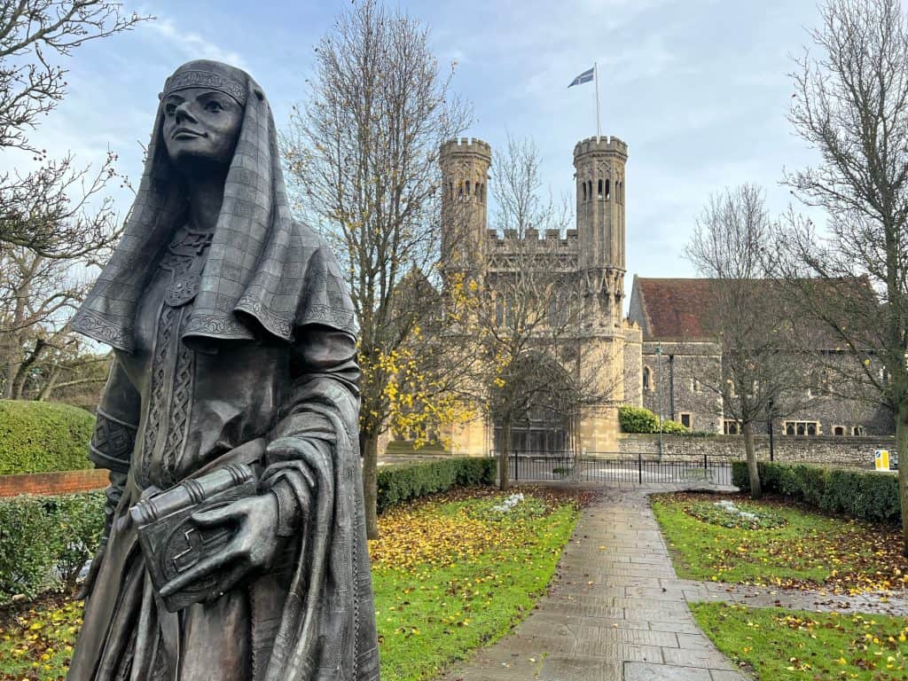 The best of Canterbury: The Fyndon Gate Tower with Queen Bertha statue in the front. The grass is covered with leaves during the winter months.