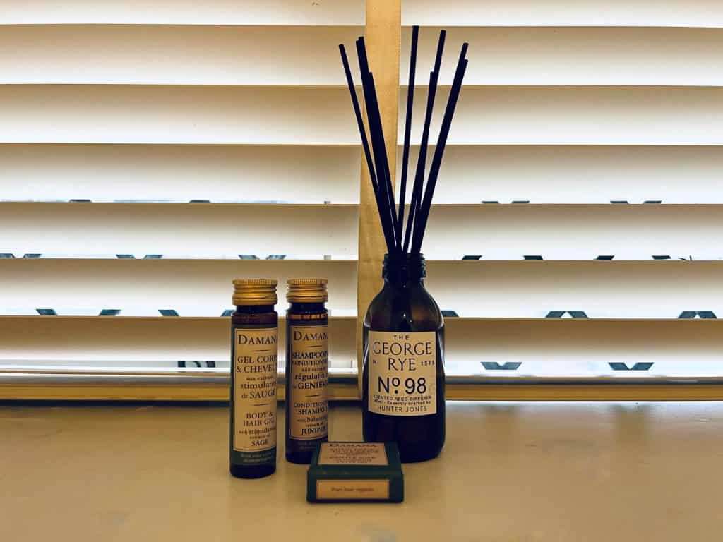 The Falstaff, Canterbury: Cosy Room Fragrance diffuser with bath product bottles on the window sill with white blinds in the background