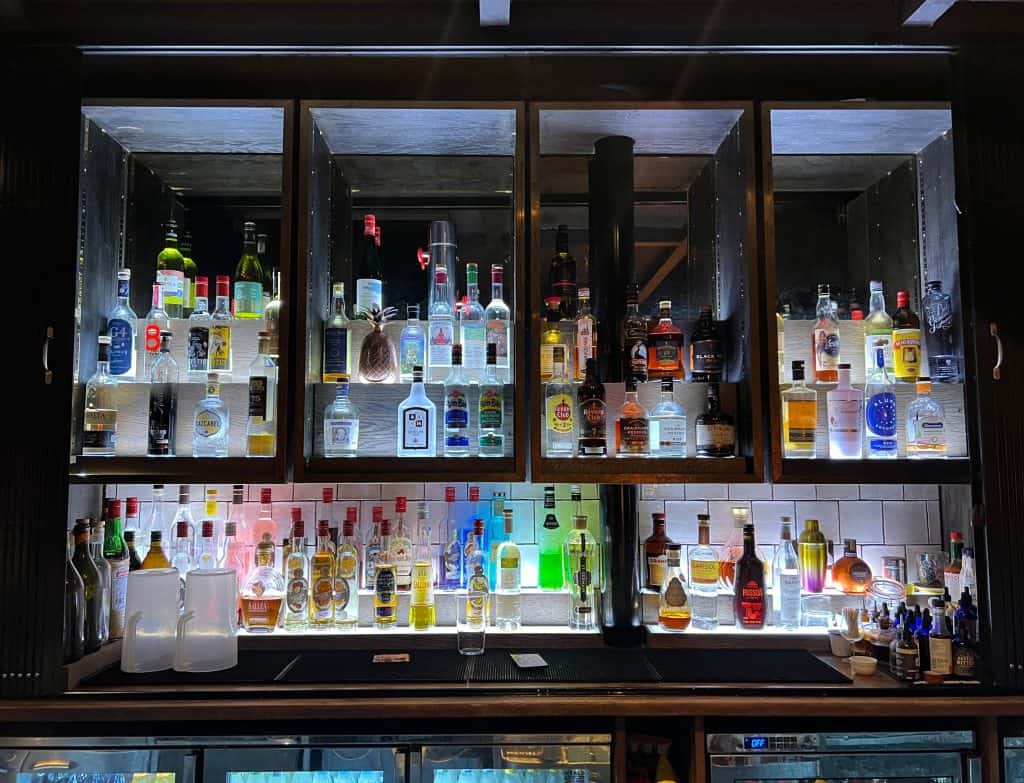 Drinks at The Falstaff Canterbury  bar. There are lots of bottle sof spirits lit up against the mirrored var exterior