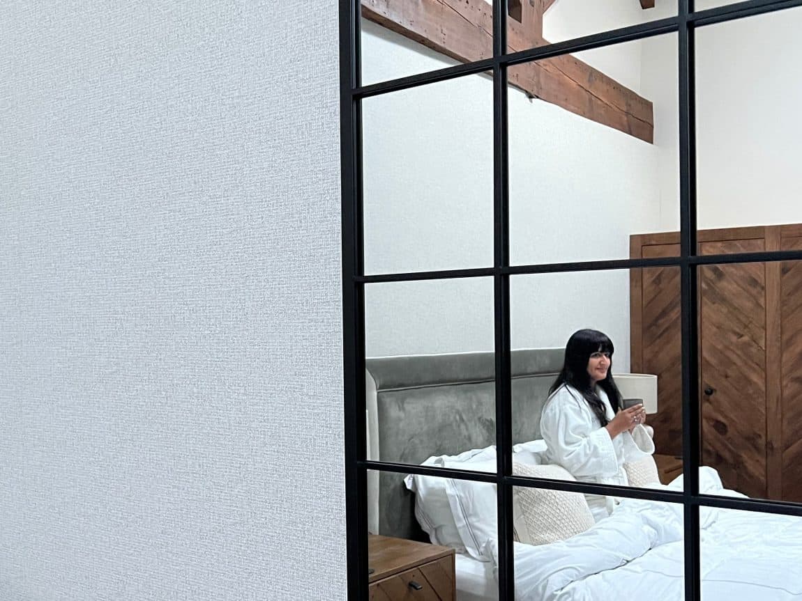 Bejal in bed framed through mirror during a. stay at The Merchant's Yard