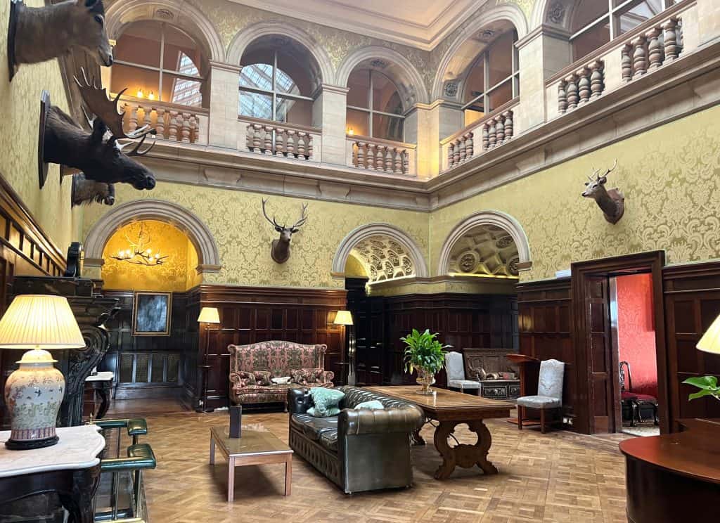 The reception room with fireplace, taxidermy and Chesterfield sofa