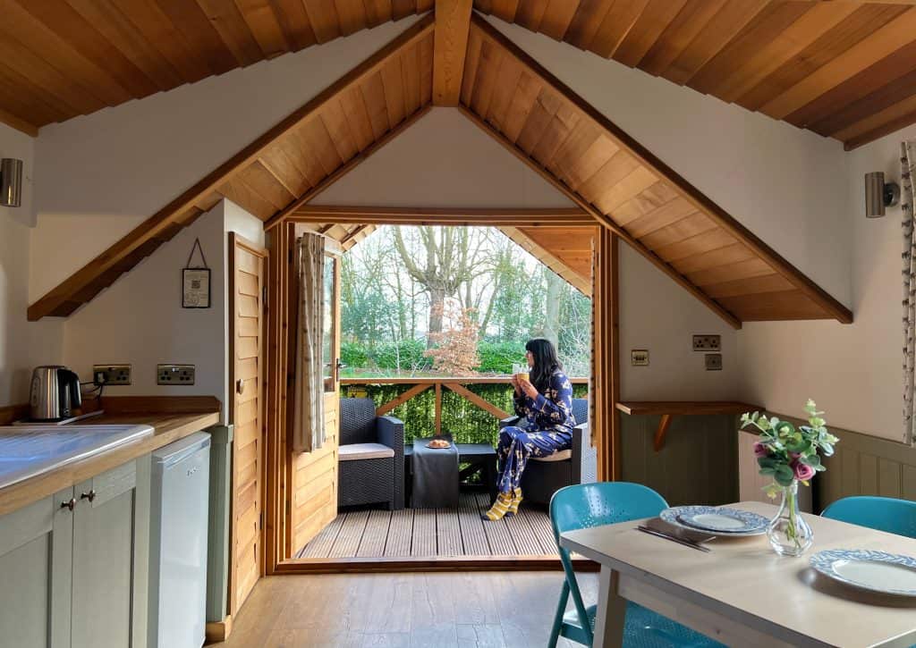 Mallory Meadows Boutique Cabin Stay: Squirrel cabin interior view from back to front with Bejal sipping tea on verandah