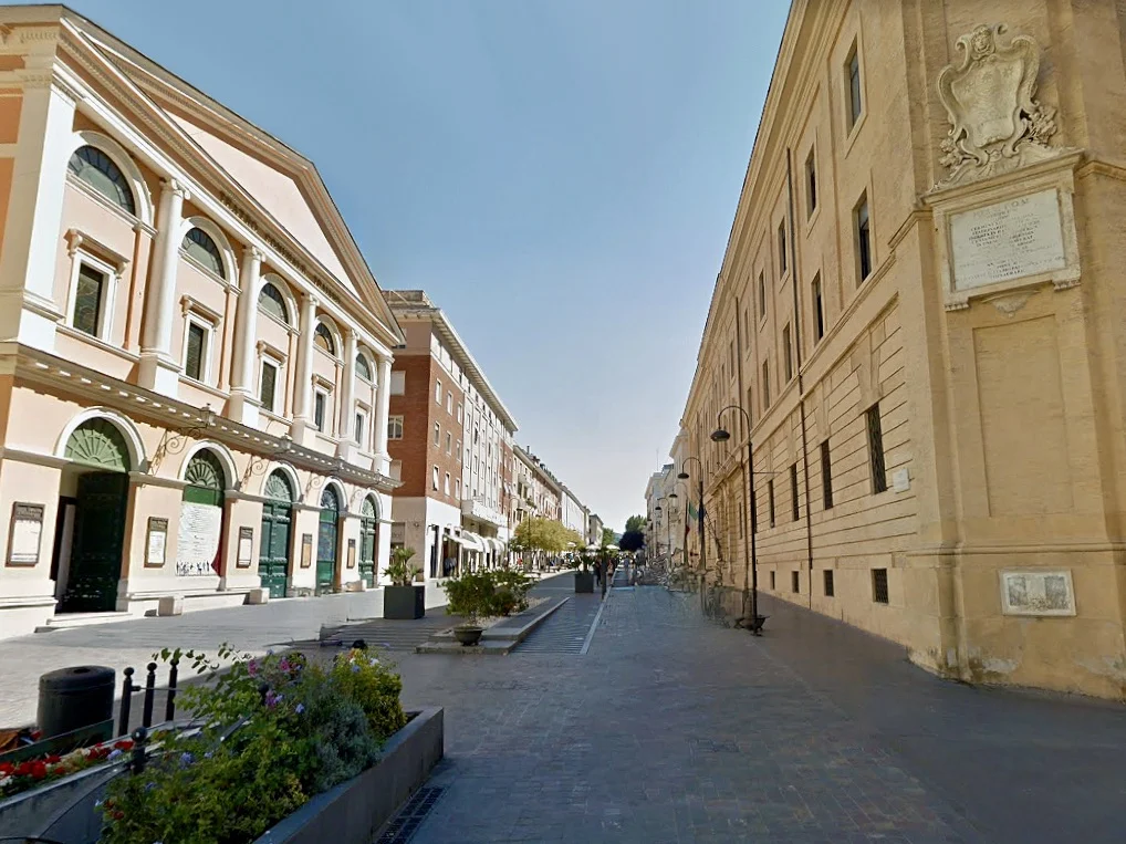 One day in Civitavecchia: The Corso Centocelle street with orange and cream buildings at either side.