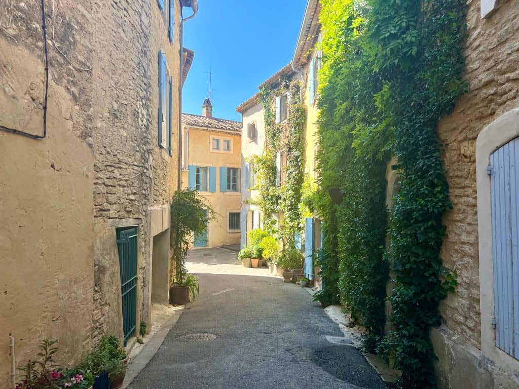 Beautiful villages to visit in Provence: Goult village street with pastal doors, and foliage lined lanes
