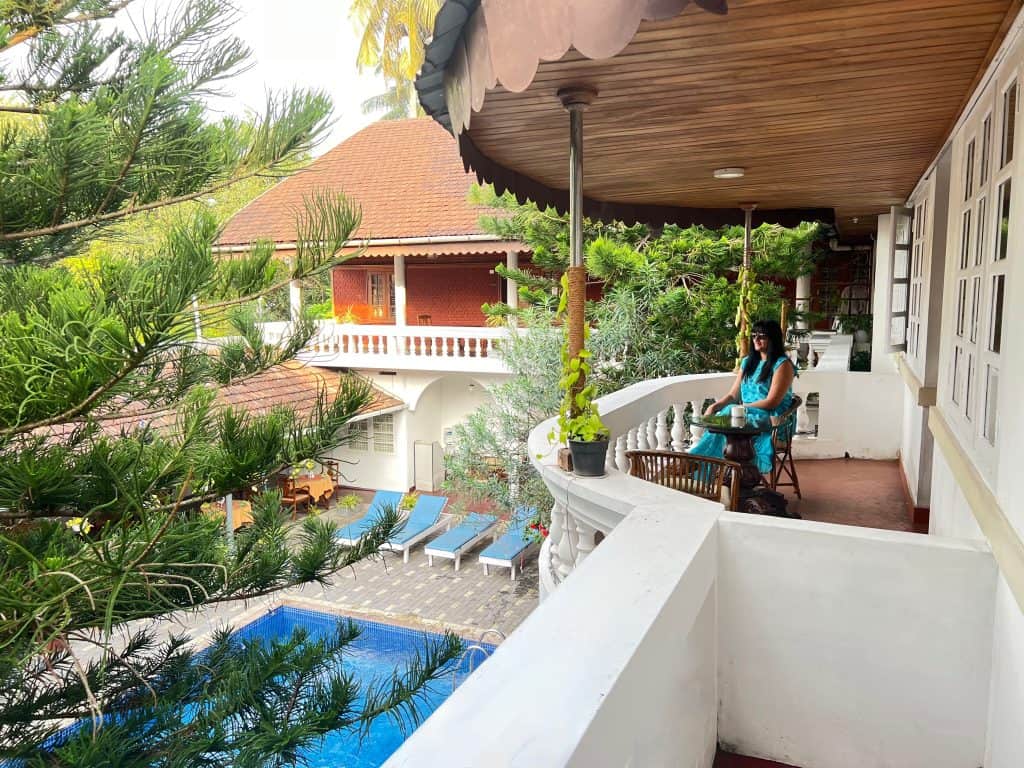 Bejal sitting on Room balcony at Abad Dutch Bungalow in Fort Kochi with view of swimming pool