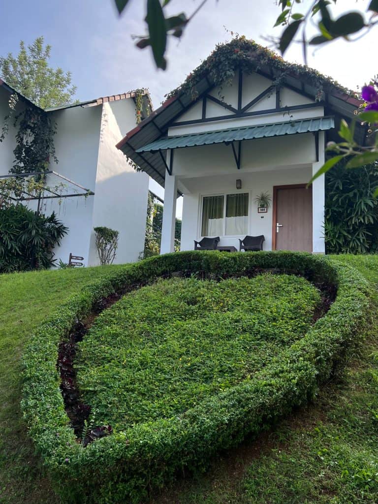 10 day Kerala itinerary, The Leaf resort cottage exterior in Munnar with a grass topiary heart in front of the poroperty entrance.