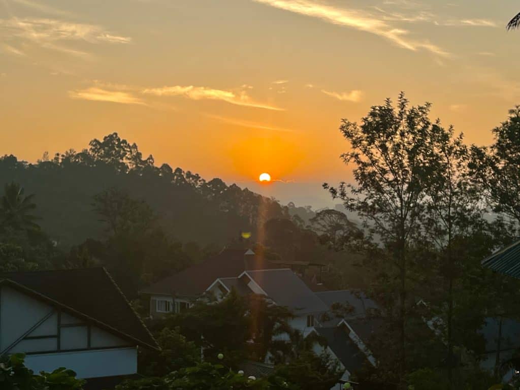 Sunrise at the viewing point at The Green Leaf, Munnar the orange/yellow sun is coming through the lush hills and plantastions that surround the property.