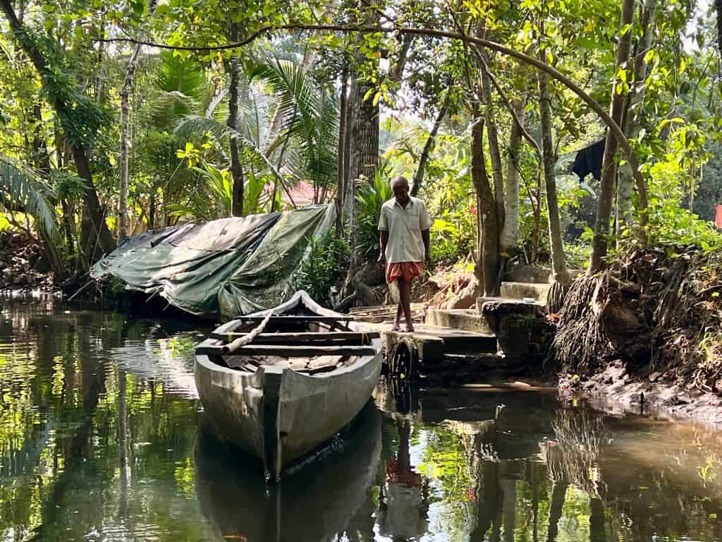 Authentic tours and activities in Kerala: Vaikom small canal with fishing boats and local man standing at canal bank