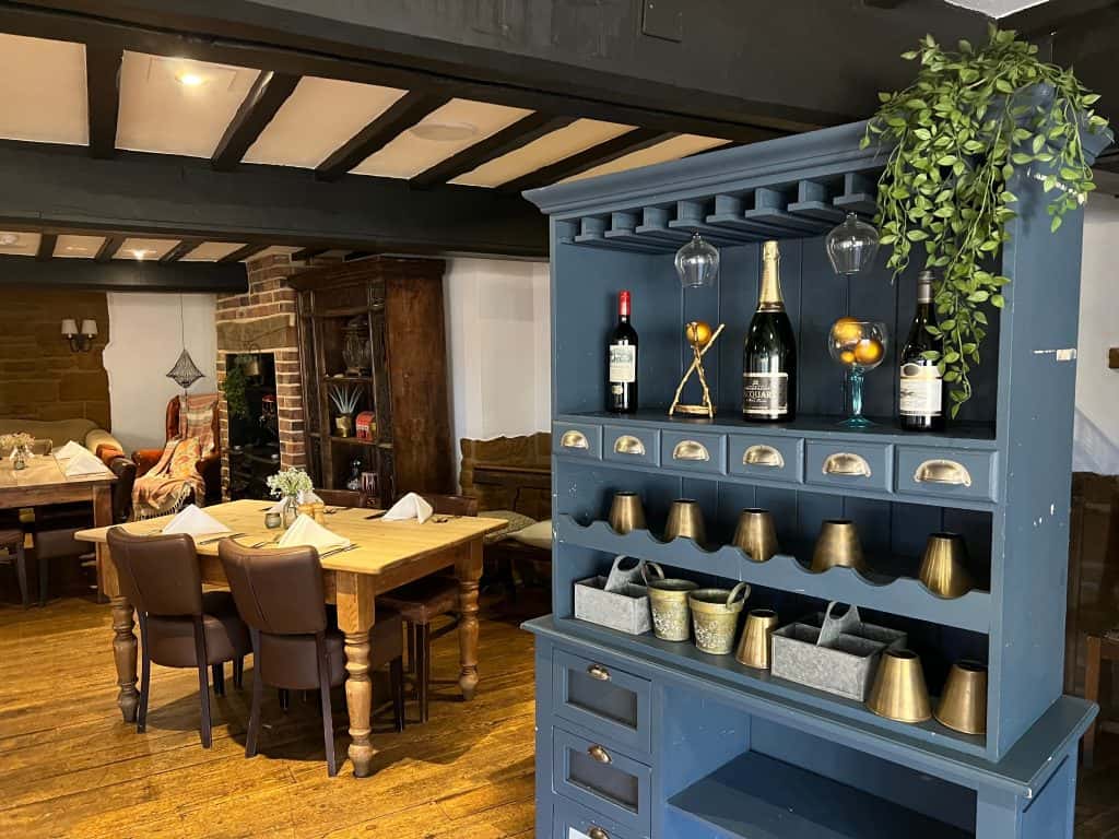 Indian food & Rooms Marquess of Exeter: blue/grey sideboard with supplies with table in the background