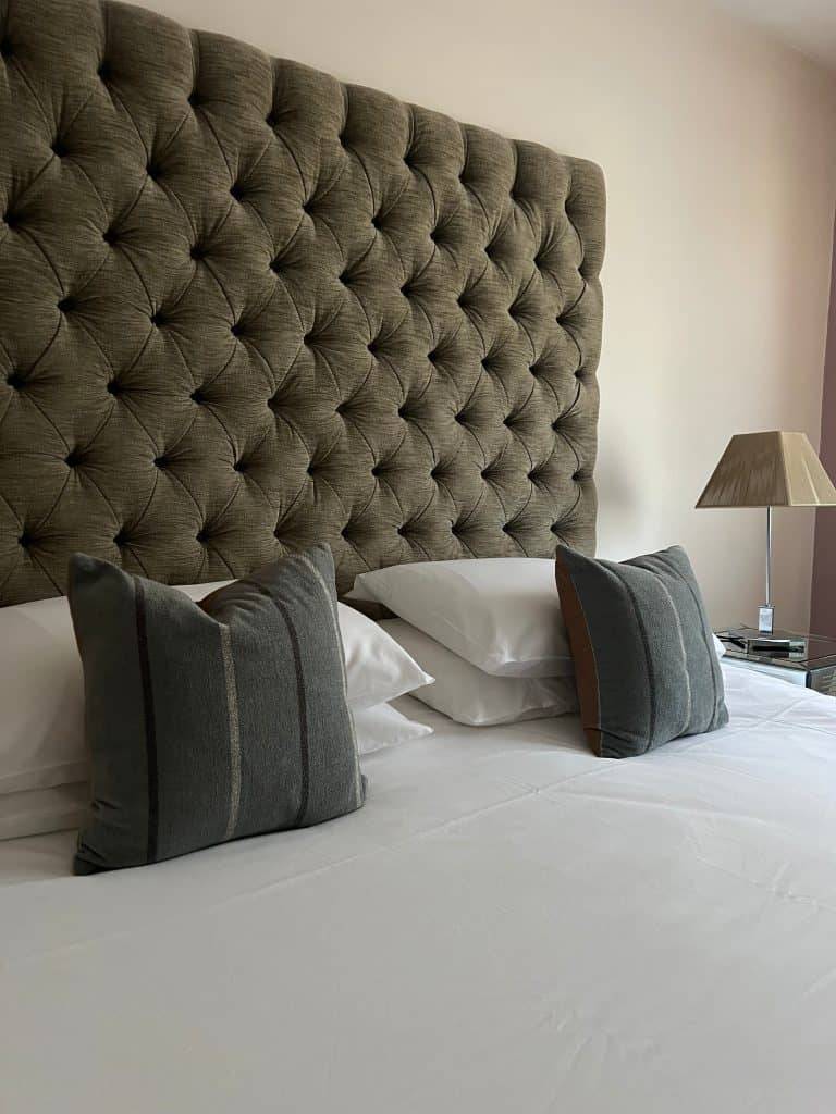 Bed with grey cushions and high headboard