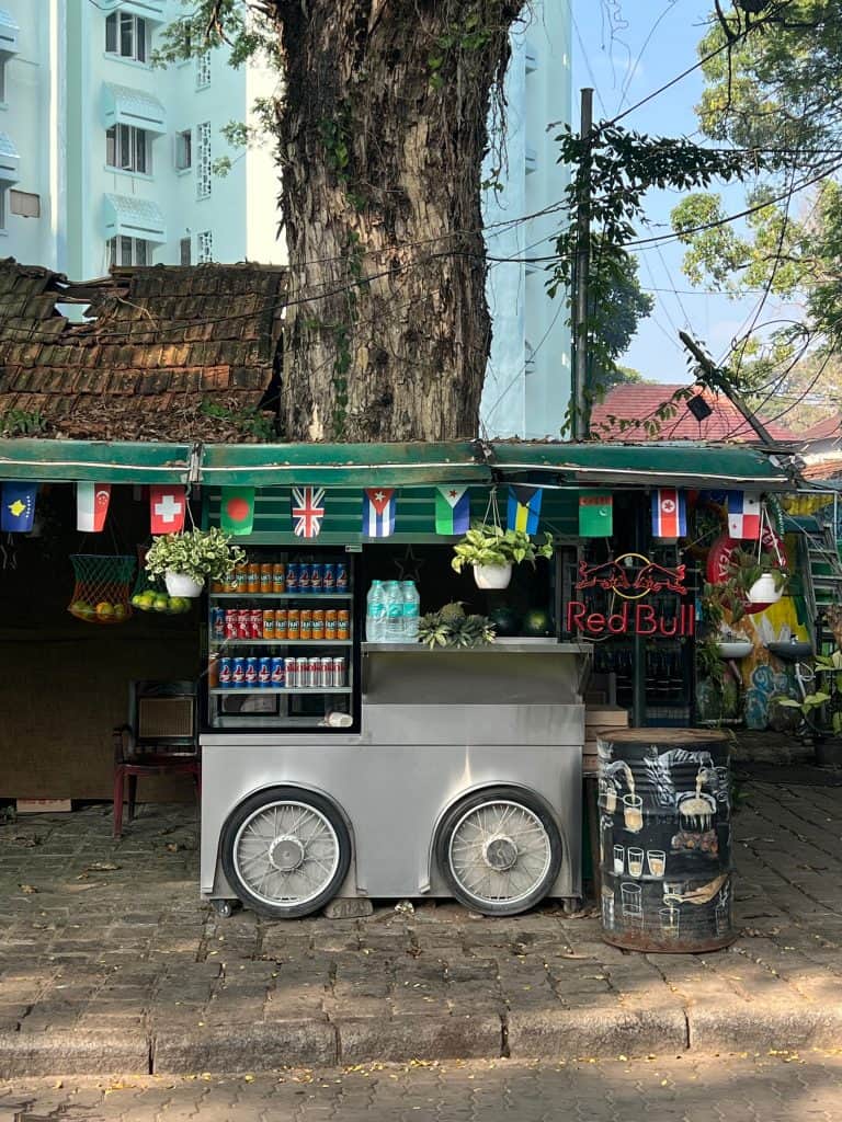 A street food stall in Fort Kochi with flags hanging outside and a counter where food is served from