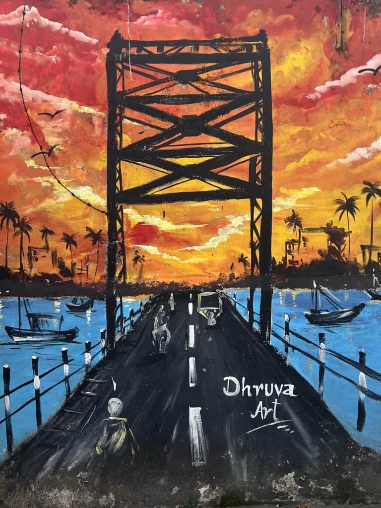 48 hours in Fort Kochi. Street art of the famous Kochi bridge with a sunset behind it and blue water flowing all around.
