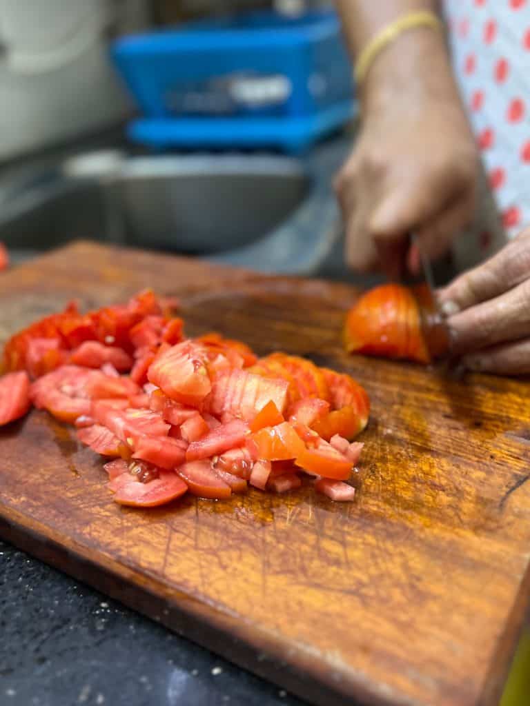 Tomatoes being chopped up by hand on a chopping board by Sheeba in Fort Kochi