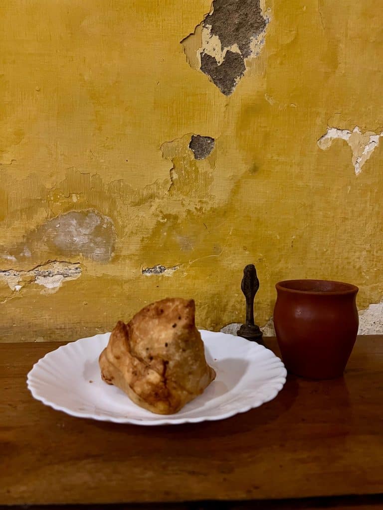 Samosa and tea against yellow wall background at Teapot cafe, Fort Kochi