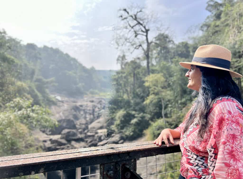  Bejal standing looking out over Mattupetty bridge. There are boulders in the background.