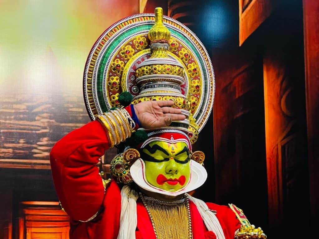 Kathakali male dancer in Fort Kochi with a painted green face and traditional make-up with costume. The costume is red, white and gold.