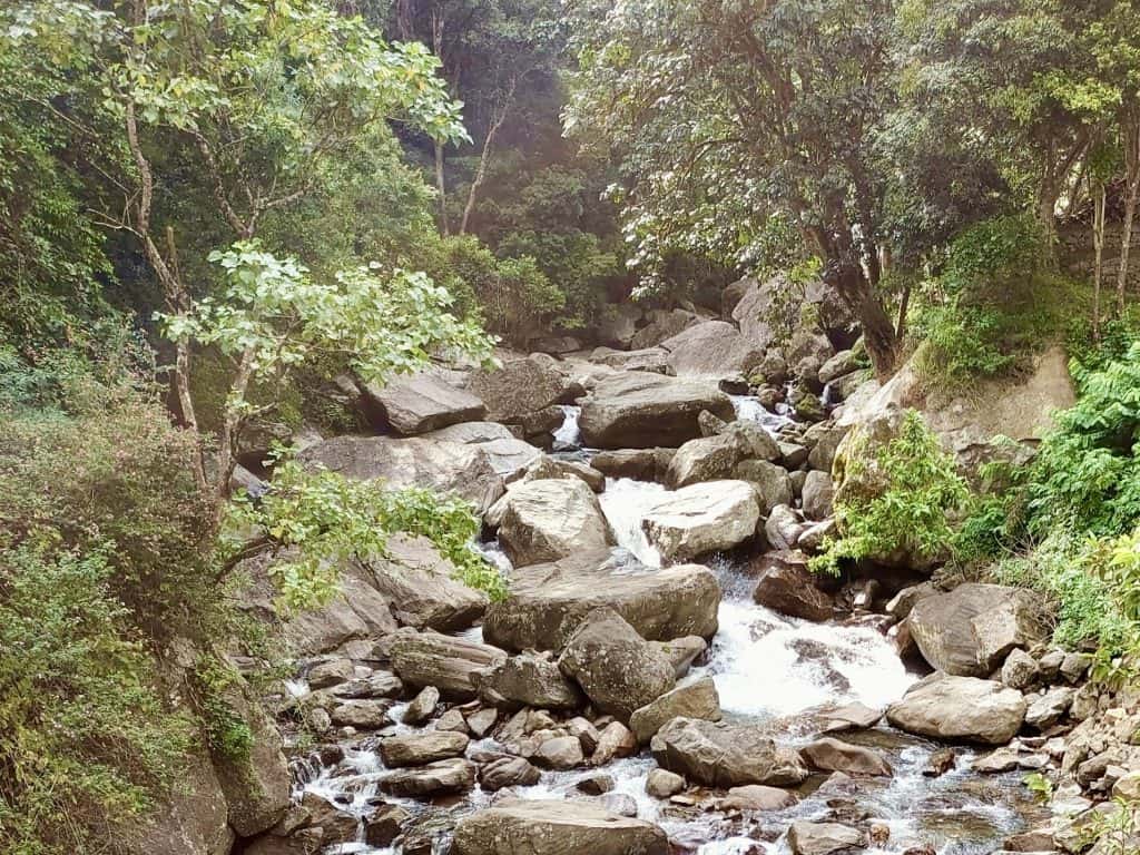 Things to do in Munnar: Lakkam waterfalls with grey boulders and a slow stream of water trickling down from the top