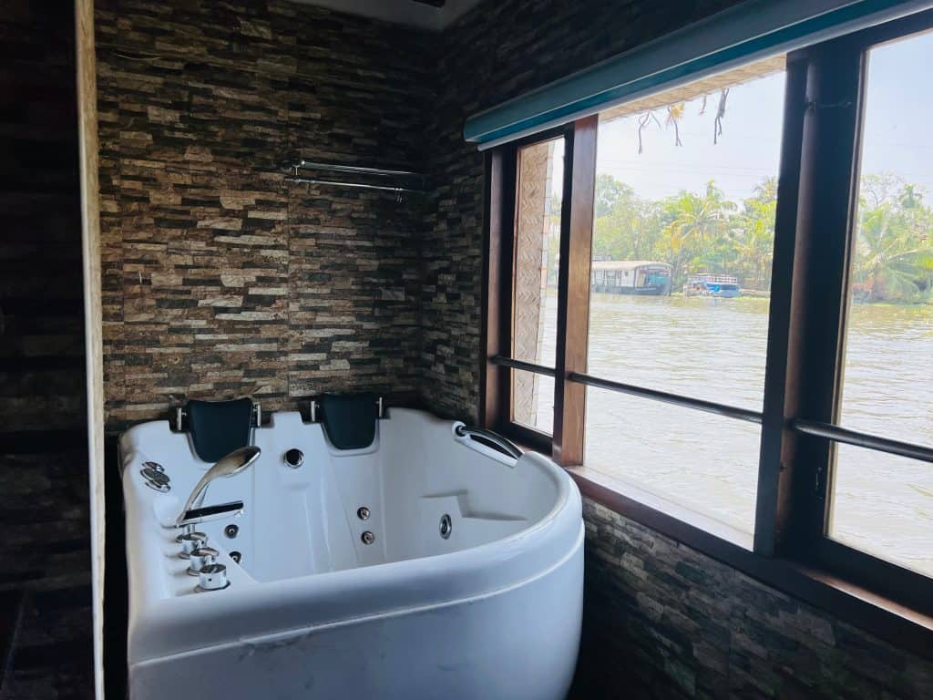 Jacuzzi bath tub in the private bathroom with views out to the backwaters through the large windows. Pickadly Royal Suite houseboat
