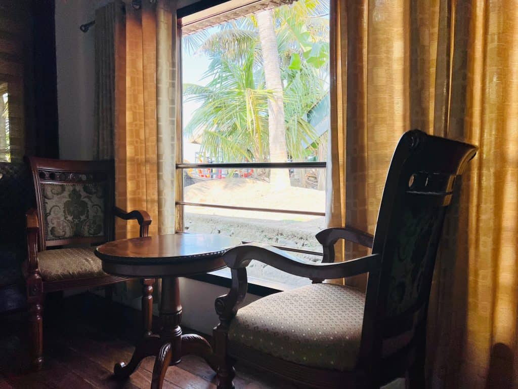 2 chairs and a table in front of a window looking out to the backwaters, in the houseboat bedroom