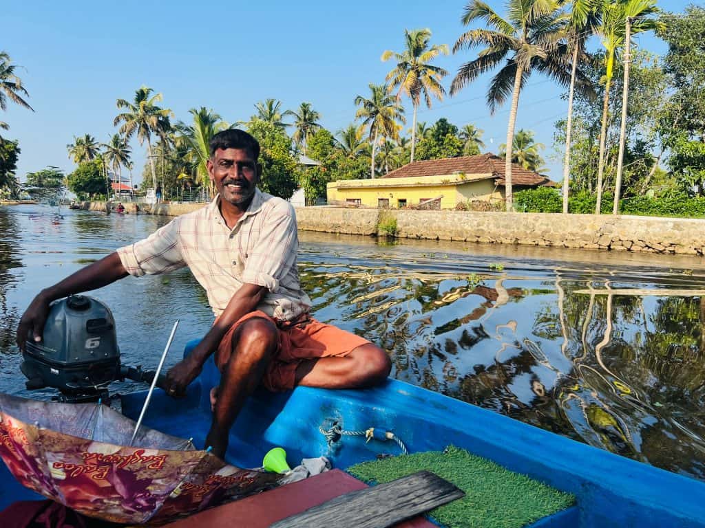 Fisherman steering the small fishing boat on the backwaters of Kerala near Alleppey